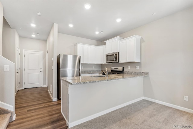 kitchen with hardwood / wood-style floors, white cabinets, sink, appliances with stainless steel finishes, and kitchen peninsula