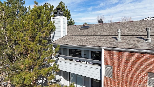 view of property exterior featuring brick siding, roof with shingles, and a chimney