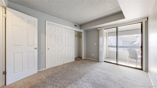 unfurnished bedroom featuring baseboards, carpet, a closet, a textured ceiling, and access to outside