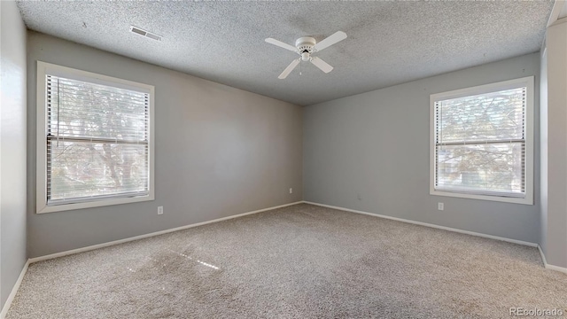 carpeted spare room with plenty of natural light, visible vents, baseboards, and a ceiling fan