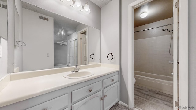 full bathroom with visible vents, shower / washtub combination, toilet, wood finished floors, and vanity