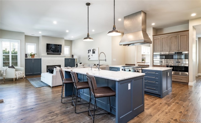295 Jersey St, Denver, CO 80220 - kitchen with a center island with sink, dark wood-type flooring, a sink, exhaust hood, and stainless steel appliances