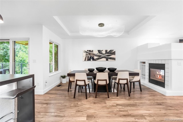 9161 W Lake Dr, Littleton, CO 80123 - dining area featuring a raised ceiling, light wood finished floors, and a glass covered fireplace