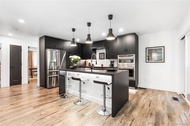 9161 W Lake Dr, Littleton, CO 80123 - kitchen featuring appliances with stainless steel finishes, dark countertops, a kitchen breakfast bar, light wood finished floors, and recessed lighting