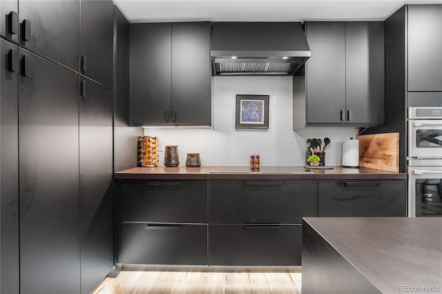9161 W Lake Dr, Littleton, CO 80123 - kitchen featuring wall chimney exhaust hood, black electric cooktop, stainless steel double oven, and dark countertops