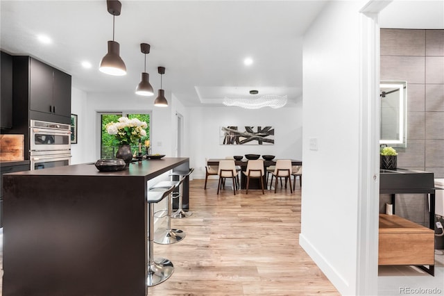 9161 W Lake Dr, Littleton, CO 80123 - kitchen with stainless steel double oven, light wood-type flooring, hanging light fixtures, dark cabinetry, and recessed lighting