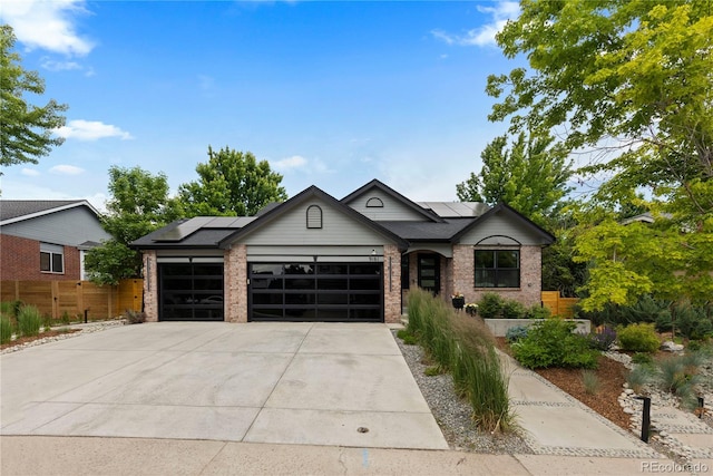 9161 W Lake Dr, Littleton, CO 80123 - view of front of house featuring brick siding, a garage, roof mounted solar panels, and concrete driveway