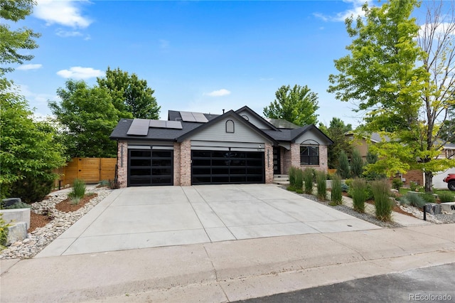 9161 W Lake Dr, Littleton, CO 80123 - view of front of property with a garage, roof mounted solar panels, brick siding, and concrete driveway