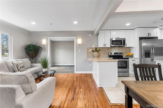 kitchen with backsplash, open floor plan, light countertops, white cabinets, and stainless steel appliances