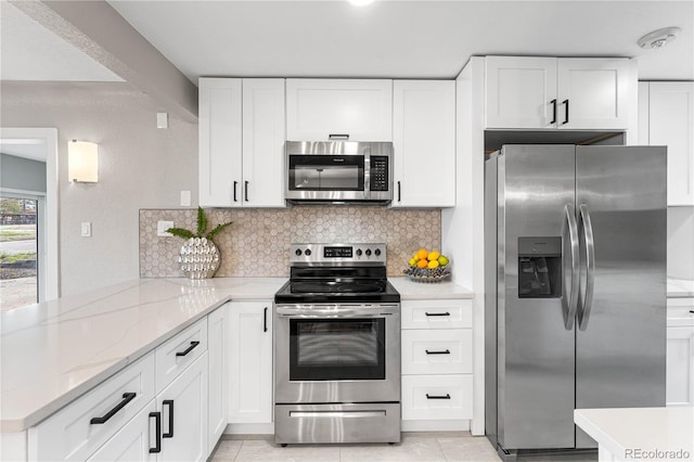 kitchen with white cabinetry, a peninsula, backsplash, and appliances with stainless steel finishes