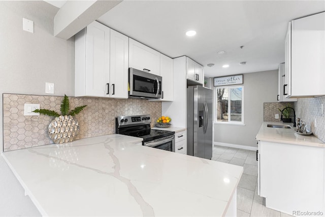 kitchen featuring a sink, appliances with stainless steel finishes, white cabinets, light tile patterned flooring, and light stone countertops