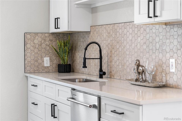 kitchen with a sink, stainless steel dishwasher, white cabinets, and light countertops