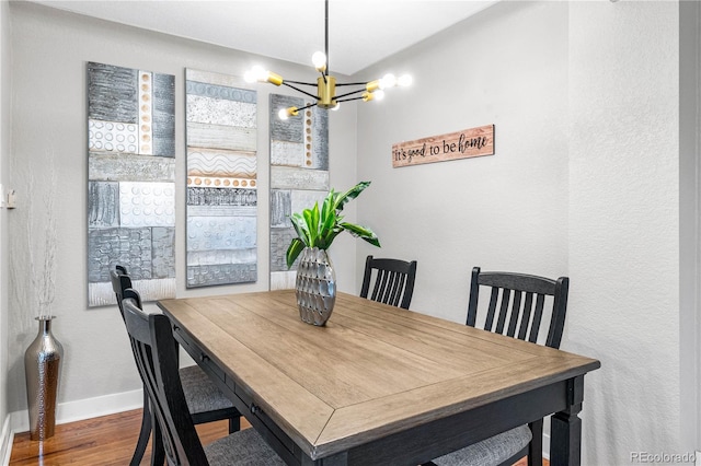 dining area featuring a chandelier, baseboards, and wood finished floors