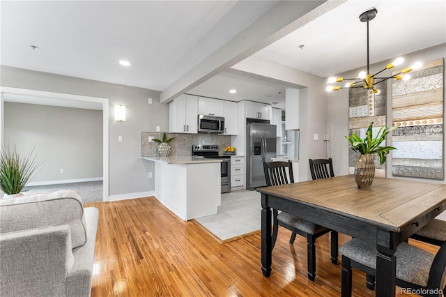 dining room featuring a chandelier, recessed lighting, baseboards, and light wood-style floors