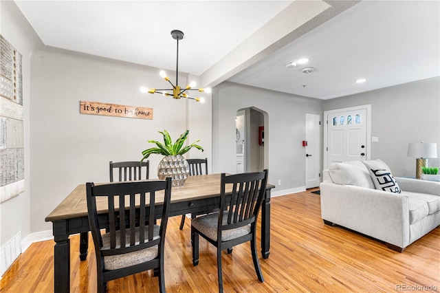 dining room with visible vents, arched walkways, light wood finished floors, and baseboards