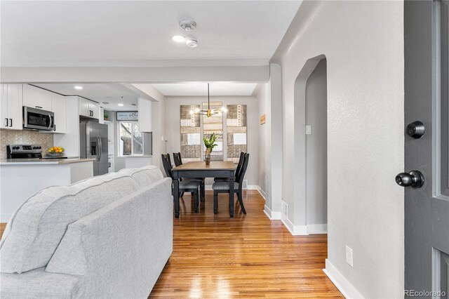 dining room featuring an inviting chandelier, light wood-style floors, and baseboards