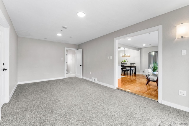 carpeted spare room with recessed lighting, baseboards, and a chandelier