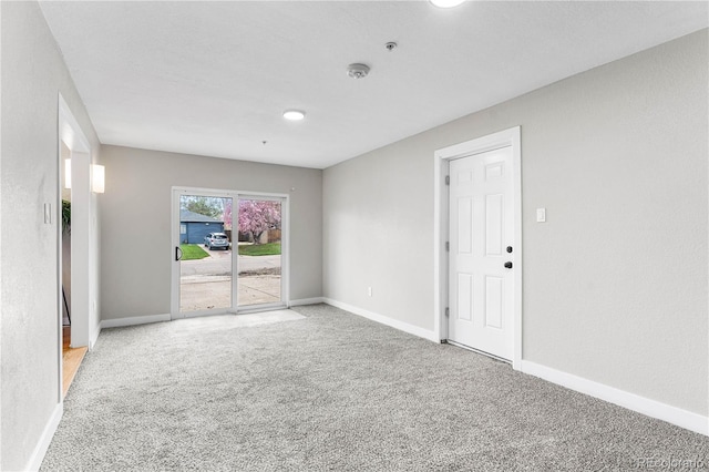 carpeted empty room featuring baseboards