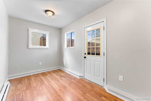 doorway with light wood-type flooring, baseboards, and baseboard heating