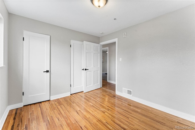 unfurnished bedroom with light wood-type flooring, visible vents, and baseboards