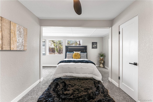 bedroom featuring a drop ceiling, baseboards, carpet flooring, and a textured wall