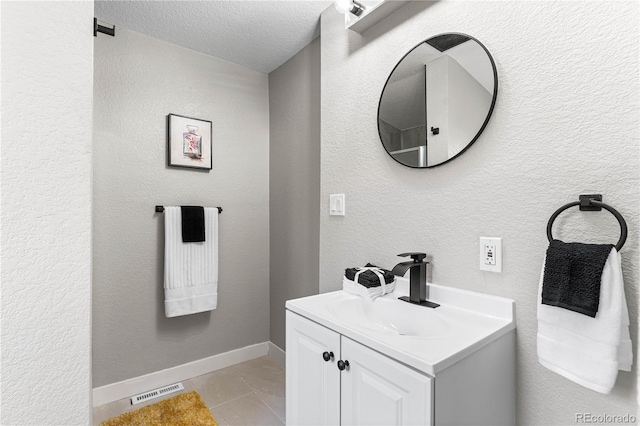 bathroom featuring visible vents, a textured ceiling, baseboards, vanity, and a textured wall