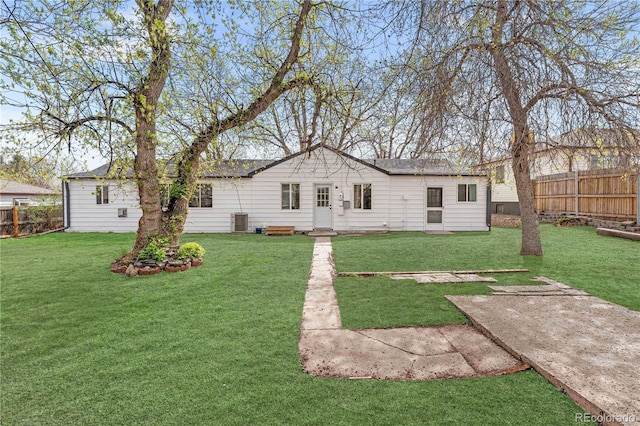 view of front facade featuring a front yard, central air condition unit, and fence