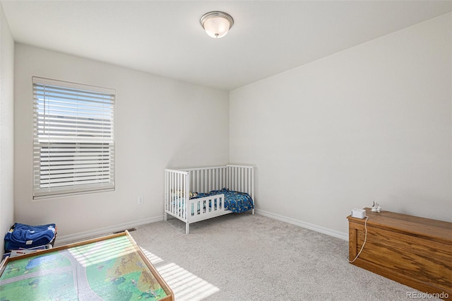 carpeted bedroom featuring a nursery area