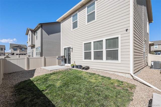 back of property with a yard, cooling unit, and a patio