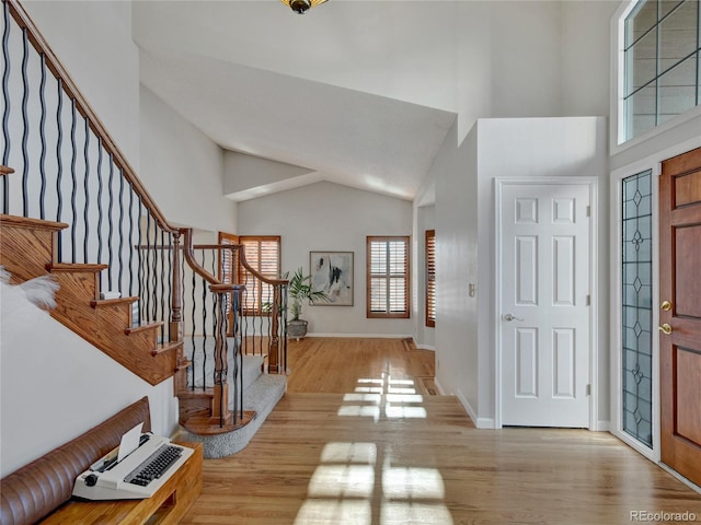 foyer entrance featuring a towering ceiling and light wood-type flooring