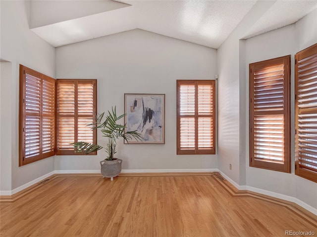 empty room featuring lofted ceiling and light wood-type flooring