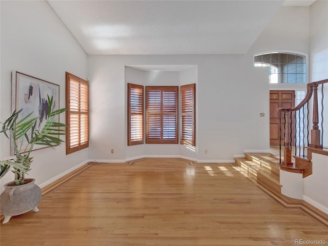 interior space featuring a towering ceiling and light hardwood / wood-style floors