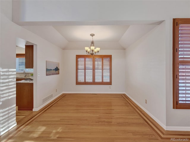 unfurnished dining area featuring light hardwood / wood-style floors, vaulted ceiling, and a notable chandelier