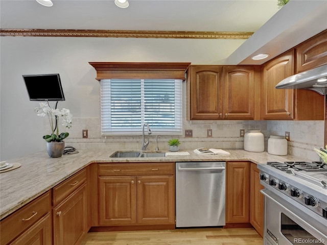 kitchen with light stone countertops, sink, backsplash, extractor fan, and appliances with stainless steel finishes