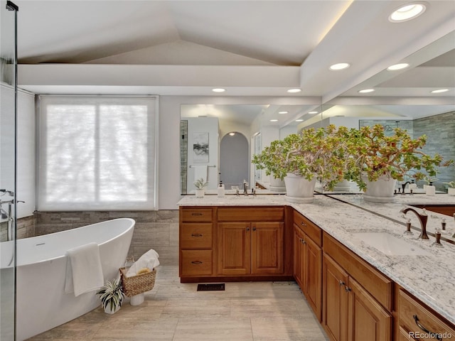 bathroom featuring tile walls, a washtub, vanity, and vaulted ceiling