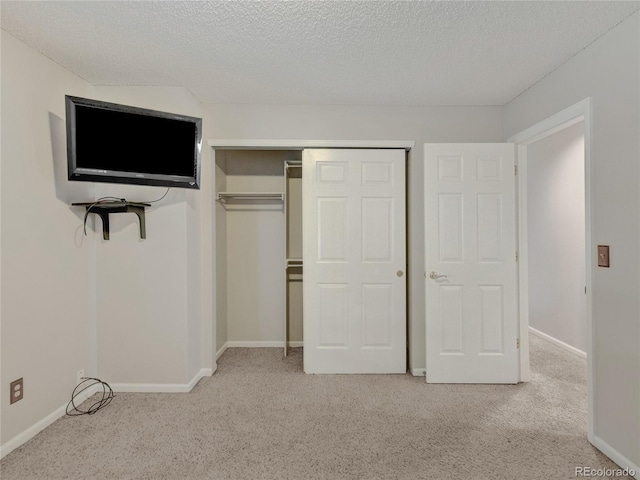 unfurnished bedroom featuring a textured ceiling, light carpet, and a closet