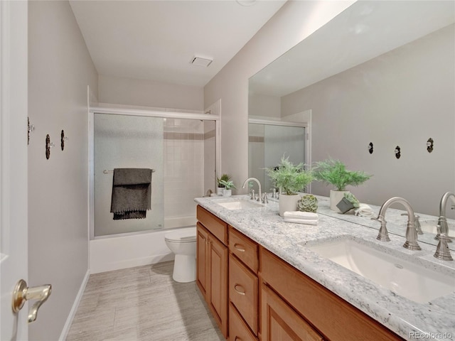 full bathroom featuring toilet, combined bath / shower with glass door, and vanity