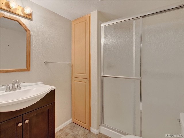 bathroom with tile patterned floors, a shower with door, and vanity