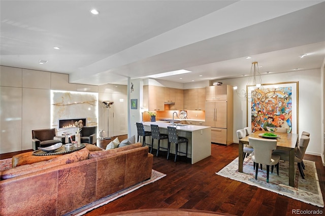 living room with recessed lighting, dark wood-style floors, and a lit fireplace