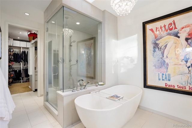 bathroom featuring an inviting chandelier, a freestanding tub, a shower stall, a spacious closet, and tile patterned floors