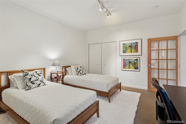 bedroom with baseboards, carpet floors, track lighting, a closet, and crown molding