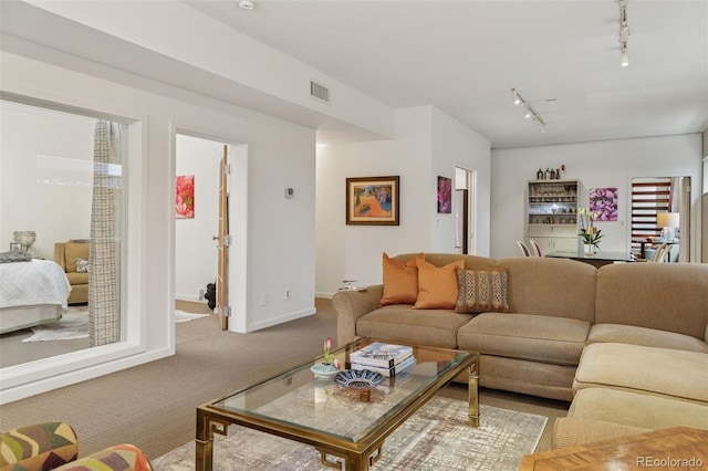 living area with visible vents, carpet floors, baseboards, and track lighting