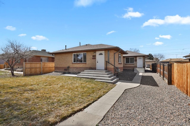 view of front of property featuring a front yard, fence, and brick siding