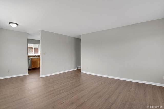 unfurnished living room featuring dark wood-style floors, visible vents, baseboards, and a sink