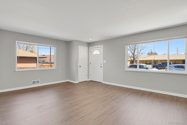 foyer featuring a wealth of natural light, visible vents, baseboards, and wood finished floors