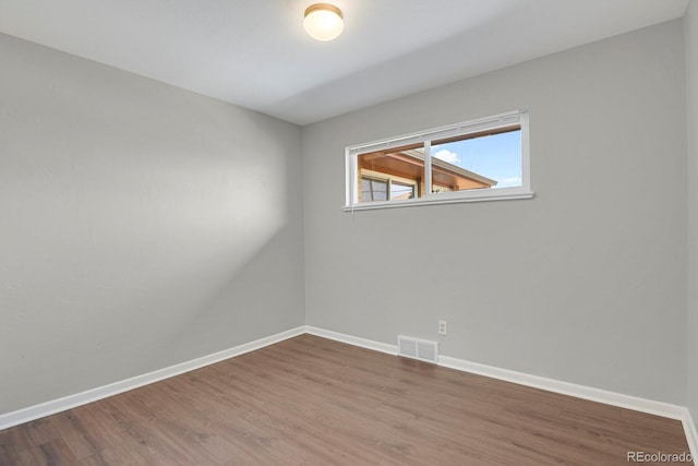 empty room with visible vents, baseboards, and wood finished floors