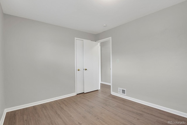 unfurnished bedroom featuring wood finished floors, baseboards, and visible vents