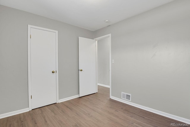 unfurnished bedroom with wood finished floors, visible vents, and baseboards