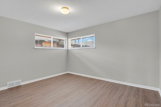 spare room with visible vents, baseboards, and wood finished floors