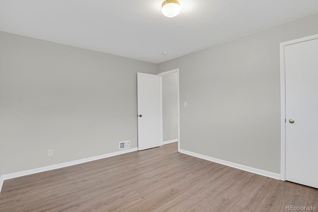 spare room featuring visible vents, baseboards, and wood finished floors